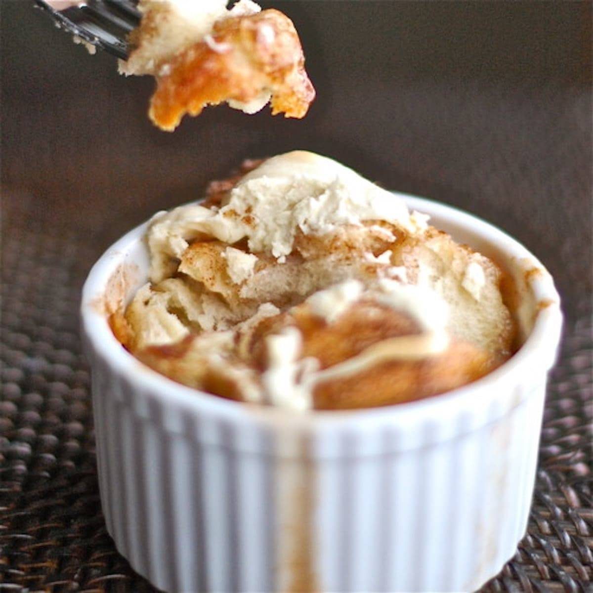 Fork removing a piece of banana monkey bread from a white dish.