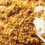 Golden breadcrumbs on a sheet pan with a spoon.