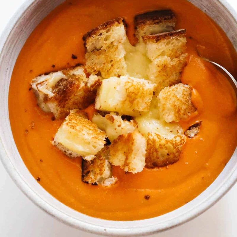 A bowl of tomato soup with the grilled cheese .